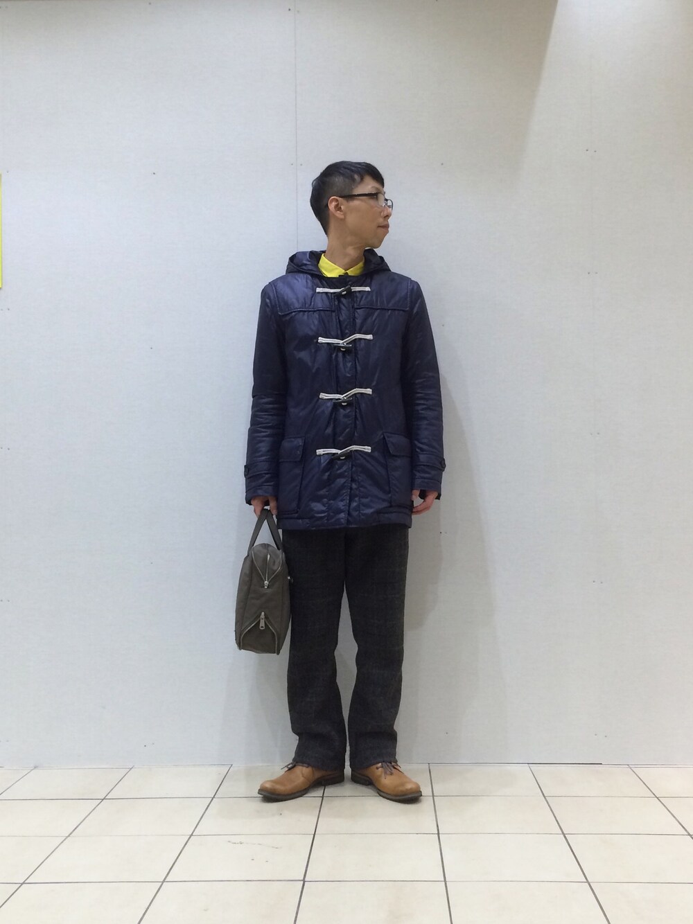 ブルー系のダッフルコート、イエロー系のシャツ/ブラウス、グレー系のトップスを着用したメンズの冬コーディネートの1枚目の写真