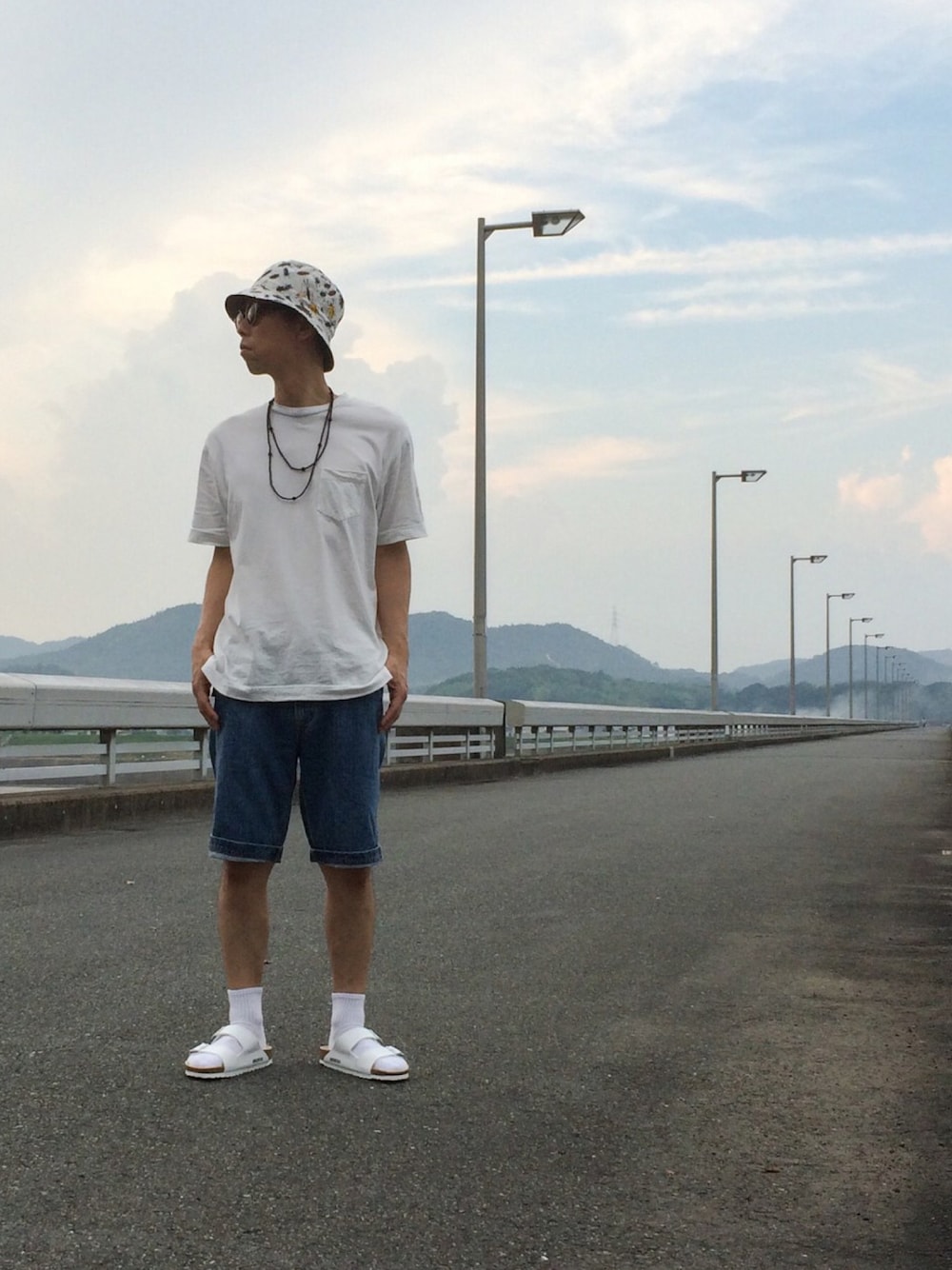 ホワイト系のTシャツ/カットソー、ブルー系のデニムパンツ、ホワイト系のサンダルを着用したメンズの夏コーディネートの1枚目の写真