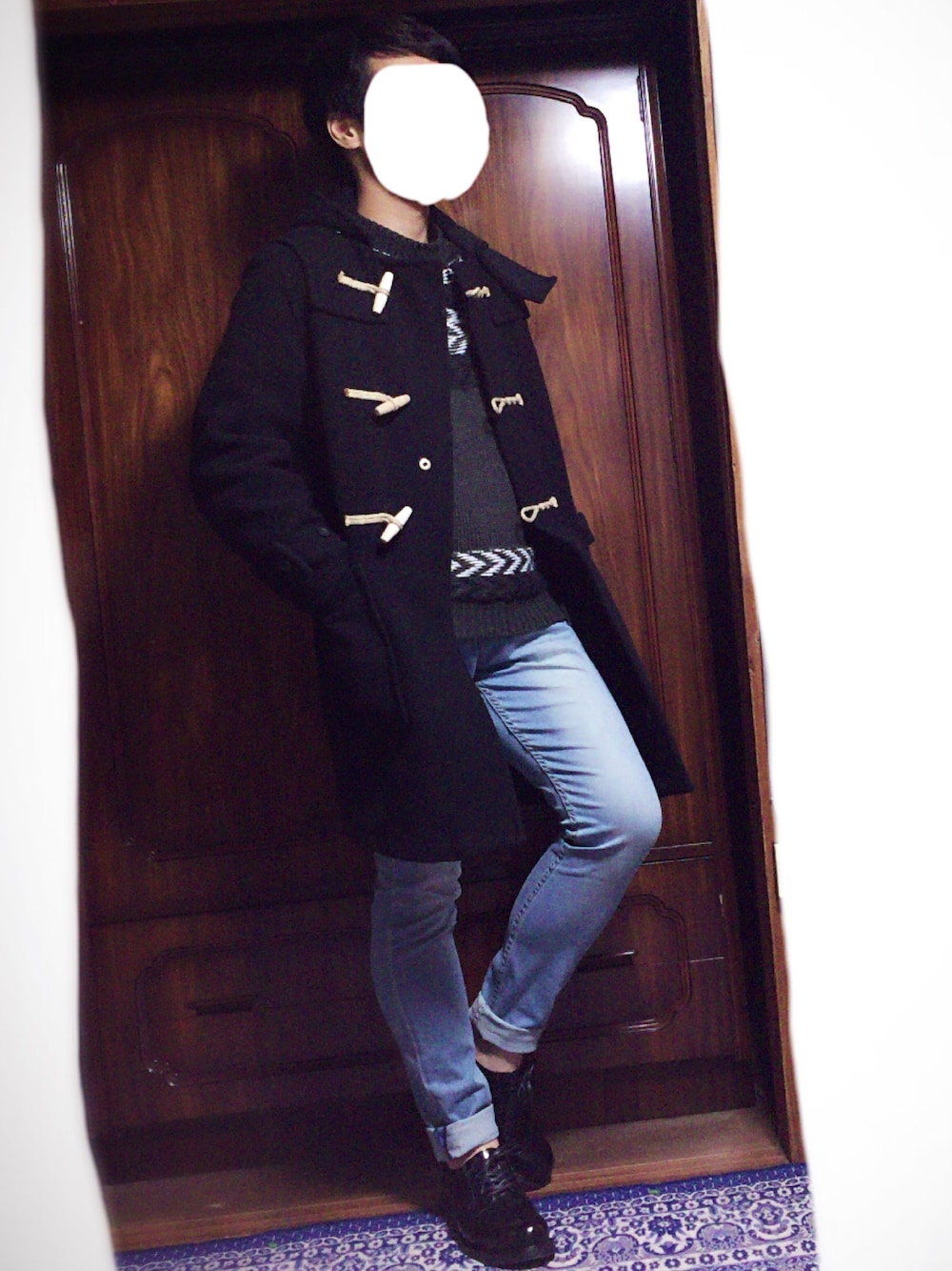 ブラック系のダッフルコート、グリーン系のニット/セーター、ブルー系のデニムパンツを着用したメンズの秋コーディネートの1枚目の写真