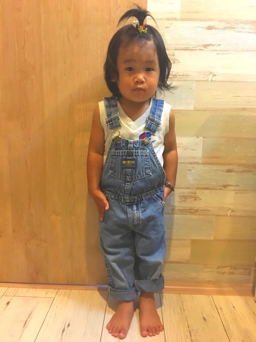 ホワイト系のタンクトップ、ブルー系のサロペット/オーバーオール、その他のヘアゴムを着用したキッズの夏コーディネートの1枚目の写真