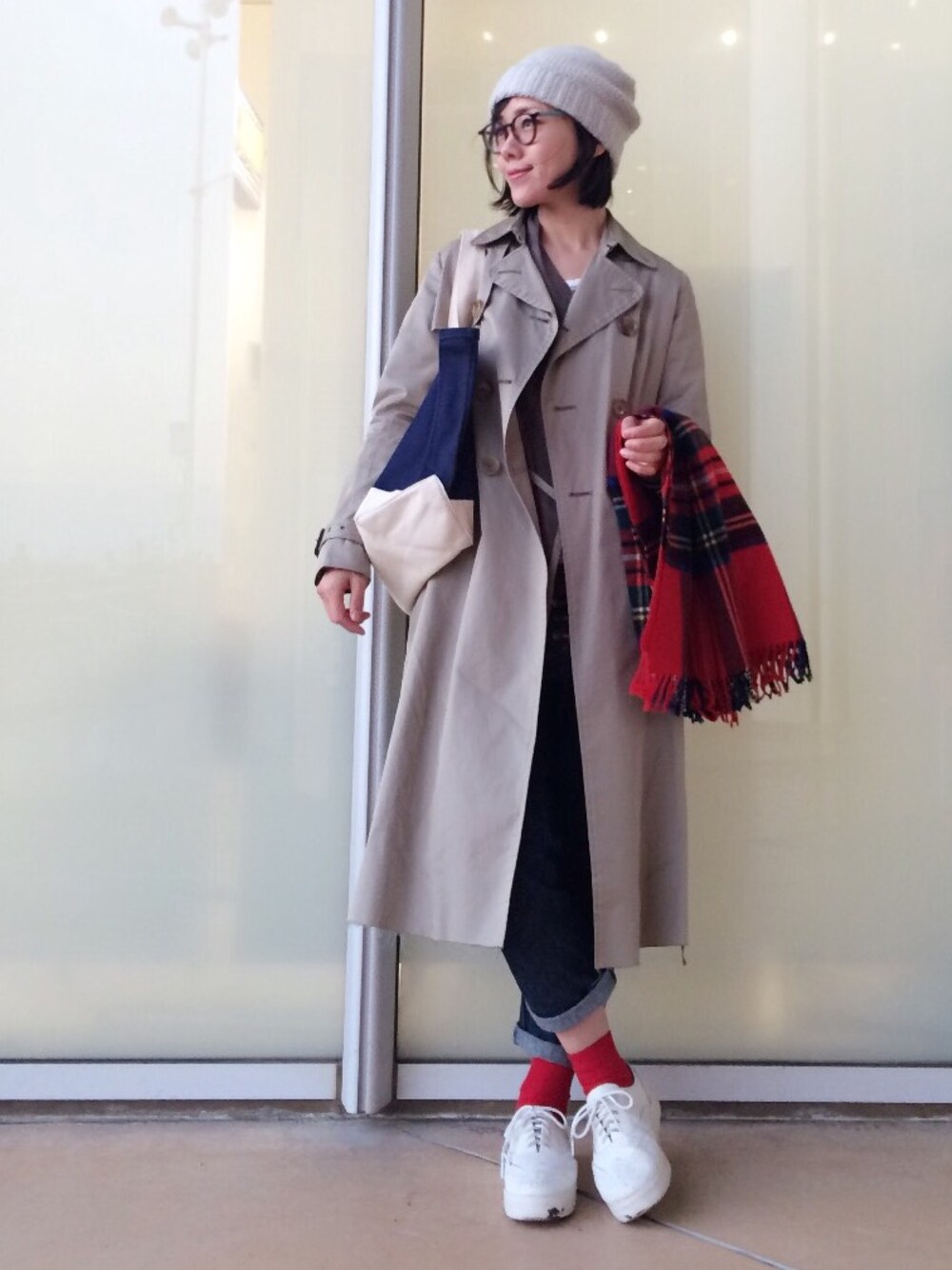 ホワイト系のスニーカー、ブルー系のデニムパンツ、ベージュ系のトレンチコートを着用したレディースの秋コーディネートの1枚目の写真