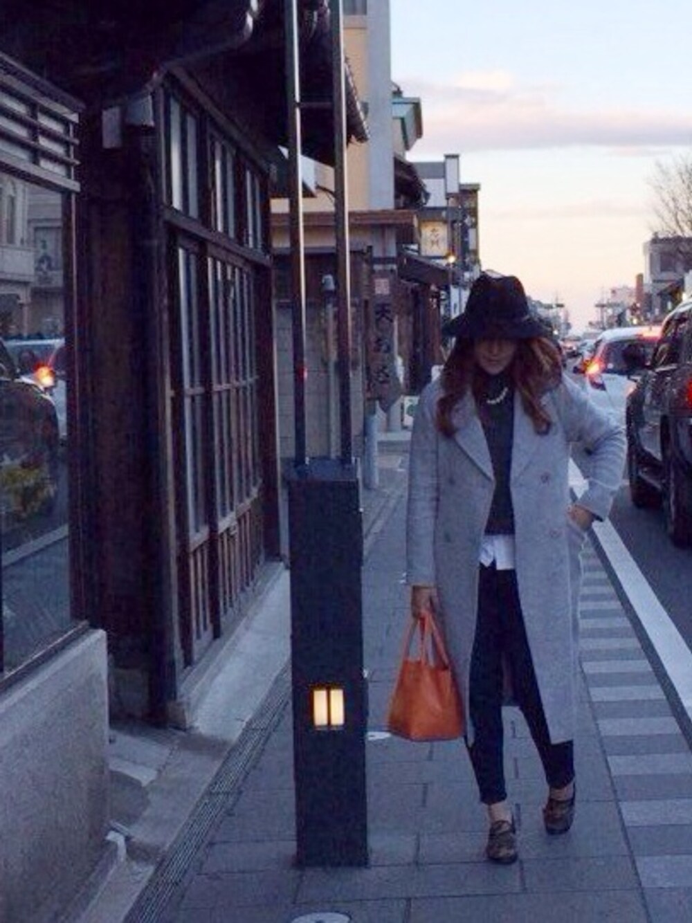 グレー系のその他アウター、オレンジ系のトートバッグ、ブラック系のハットを着用したレディースの冬コーディネートの1枚目の写真