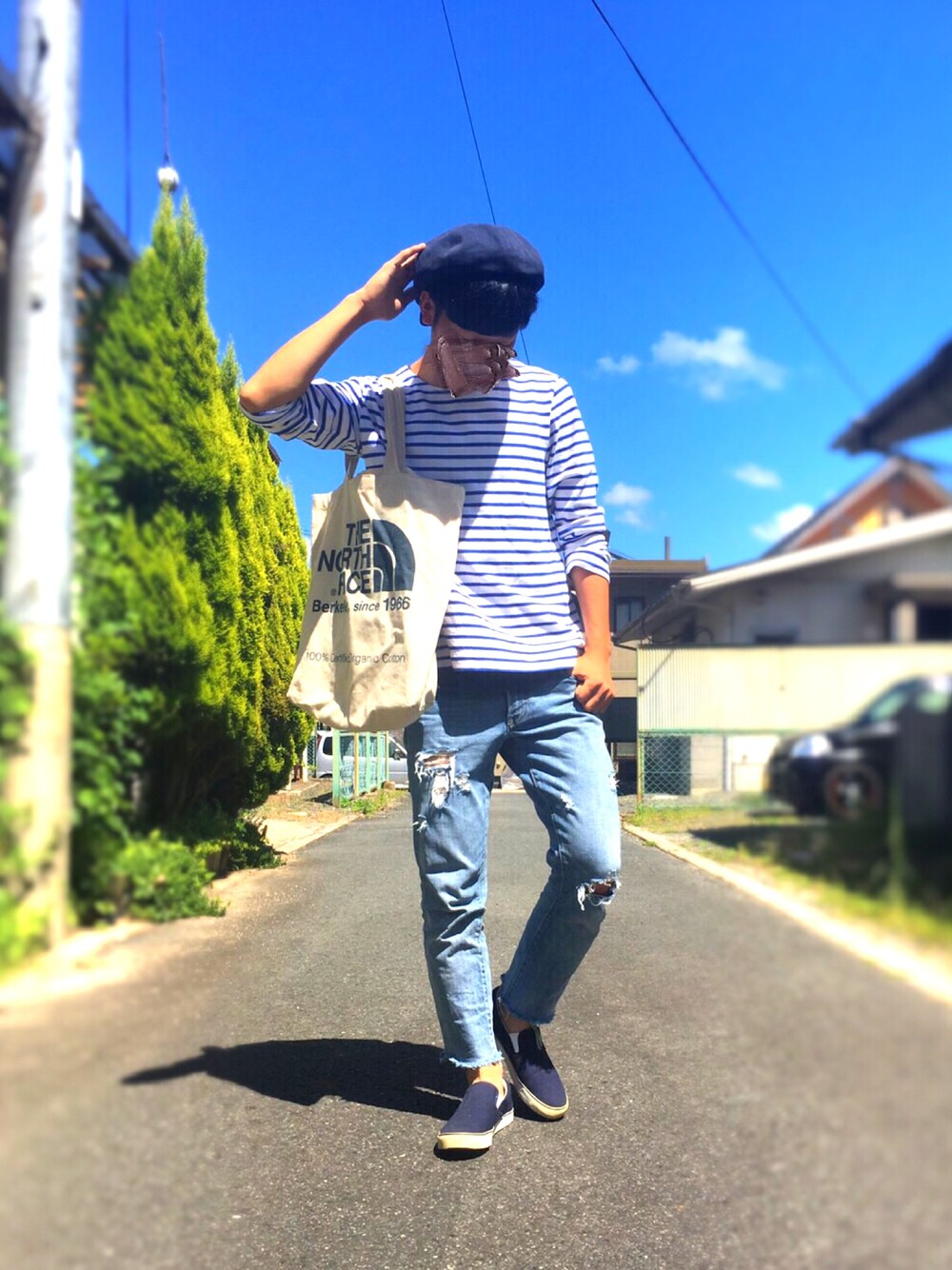 ブルー系のスリッポン、ブルー系のデニムパンツ、ホワイト系のトートバッグを着用したメンズの秋コーディネートの1枚目の写真