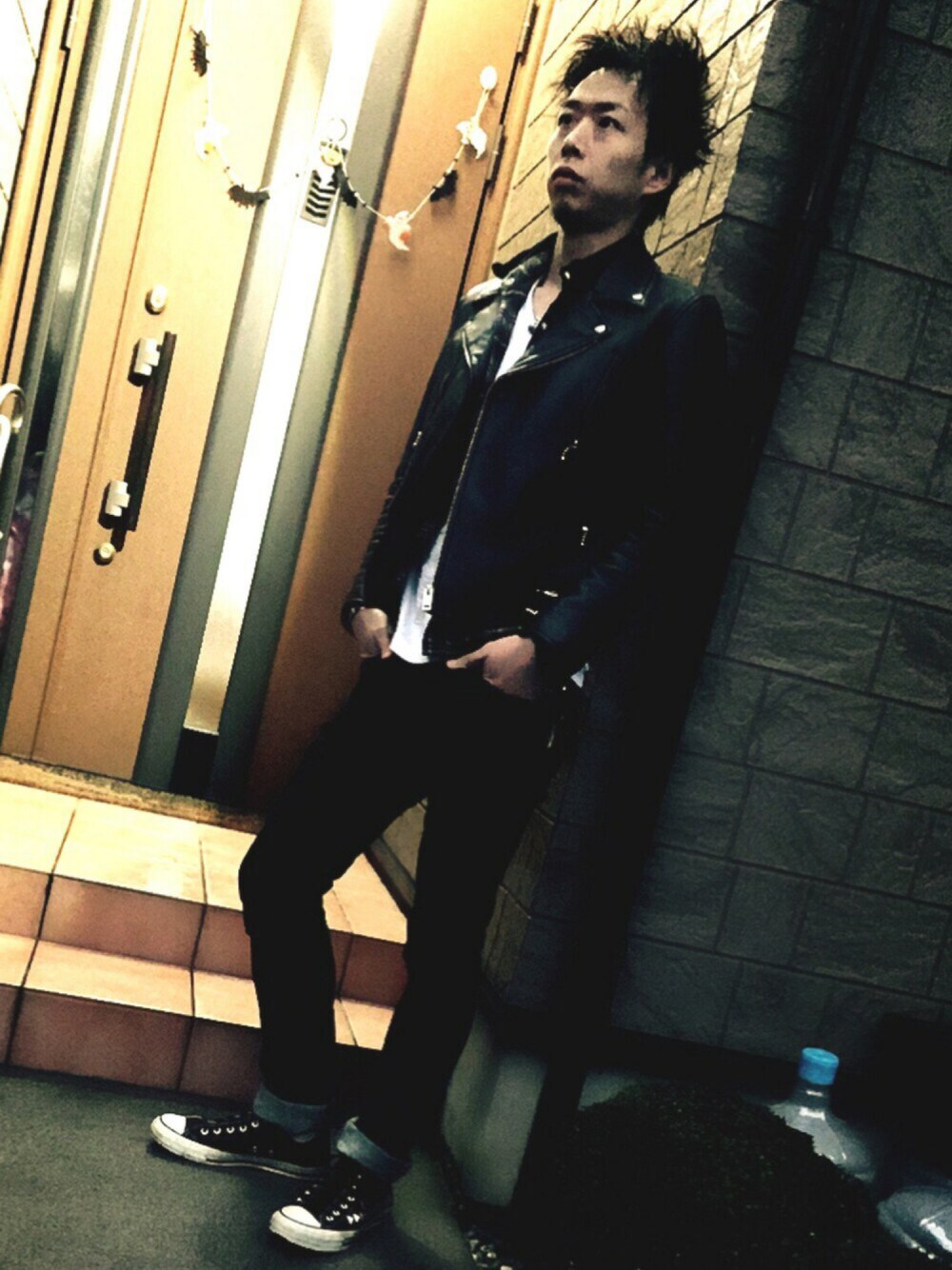 ブラック系のライダースジャケット、ブルー系のデニムパンツ、ブラック系のスニーカーを着用したメンズの秋コーディネートの1枚目の写真