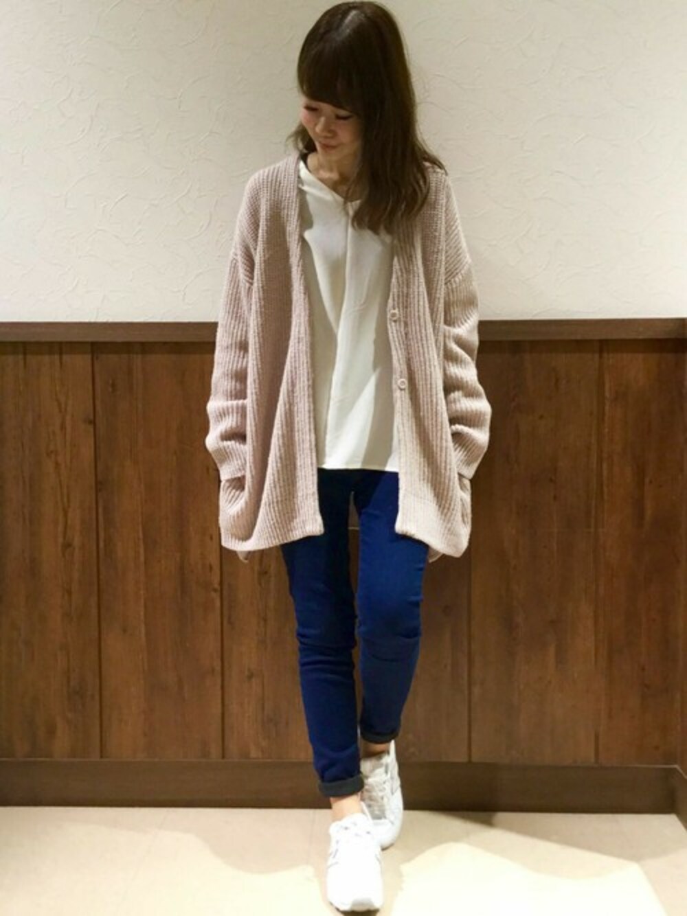 ベージュ系のカーディガン/ボレロ、ホワイト系のシャツ/ブラウス、ブルー系のデニムパンツを着用したレディースの冬コーディネートの1枚目の写真