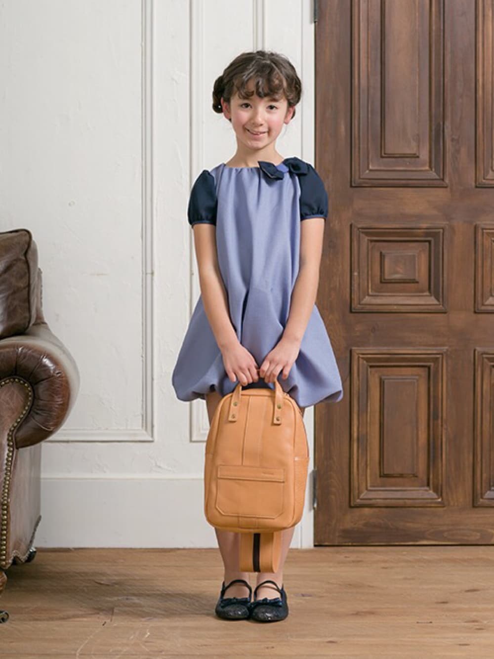 ブルー系のワンピース、ブラウン系のバックパック/リュックを着用したキッズの冬コーディネートの1枚目の写真