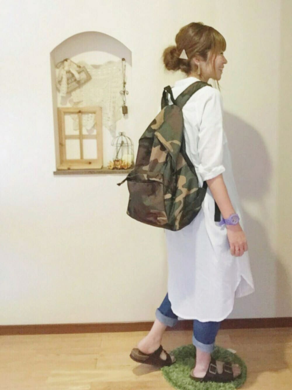 ホワイト系のシャツワンピース、ブラック系のTシャツ/カットソー、グリーン系のバックパック/リュックを着用したレディースの春コーディネートの1枚目の写真