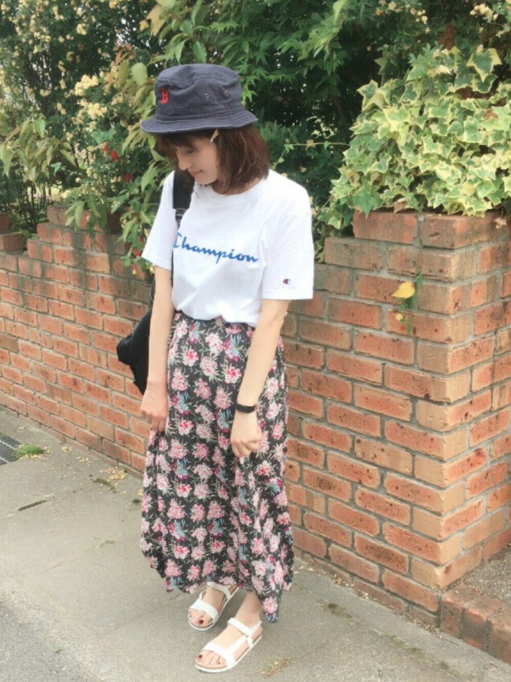 ホワイト系のTシャツ/カットソー、ブラック系のスカート、ホワイト系のサンダルを着用したレディースの春コーディネートの1枚目の写真