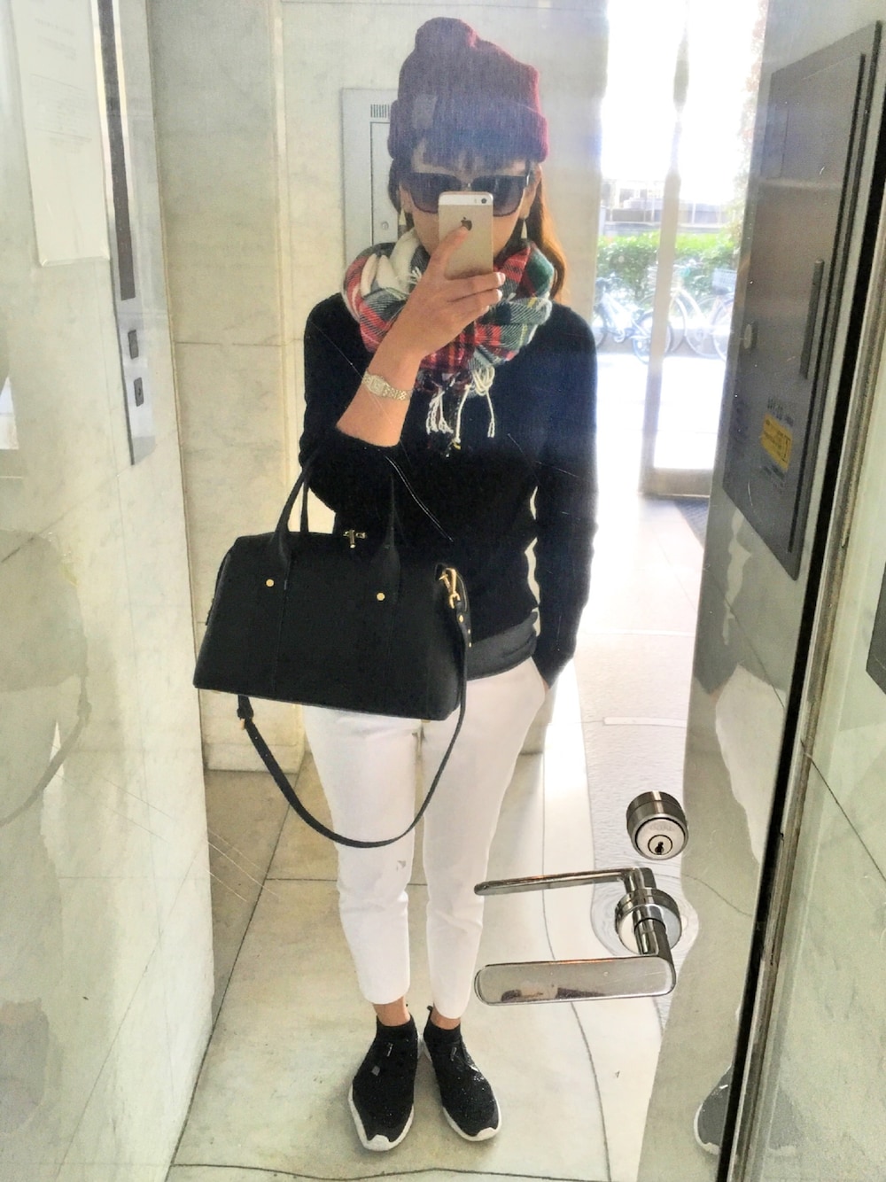 ブラック系のハンドバッグ、ブラック系のスニーカー、レッド系のニットキャップ/ビーニーを着用したレディースの秋コーディネートの1枚目の写真