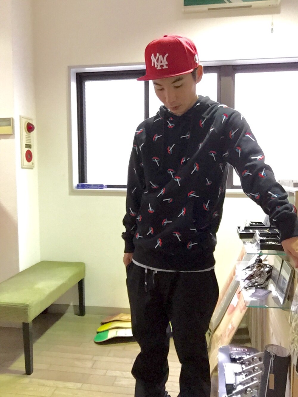 ブラック系のパーカー、ブラック系のチノパンツ、レッド系のキャップを着用したメンズの秋コーディネートの1枚目の写真