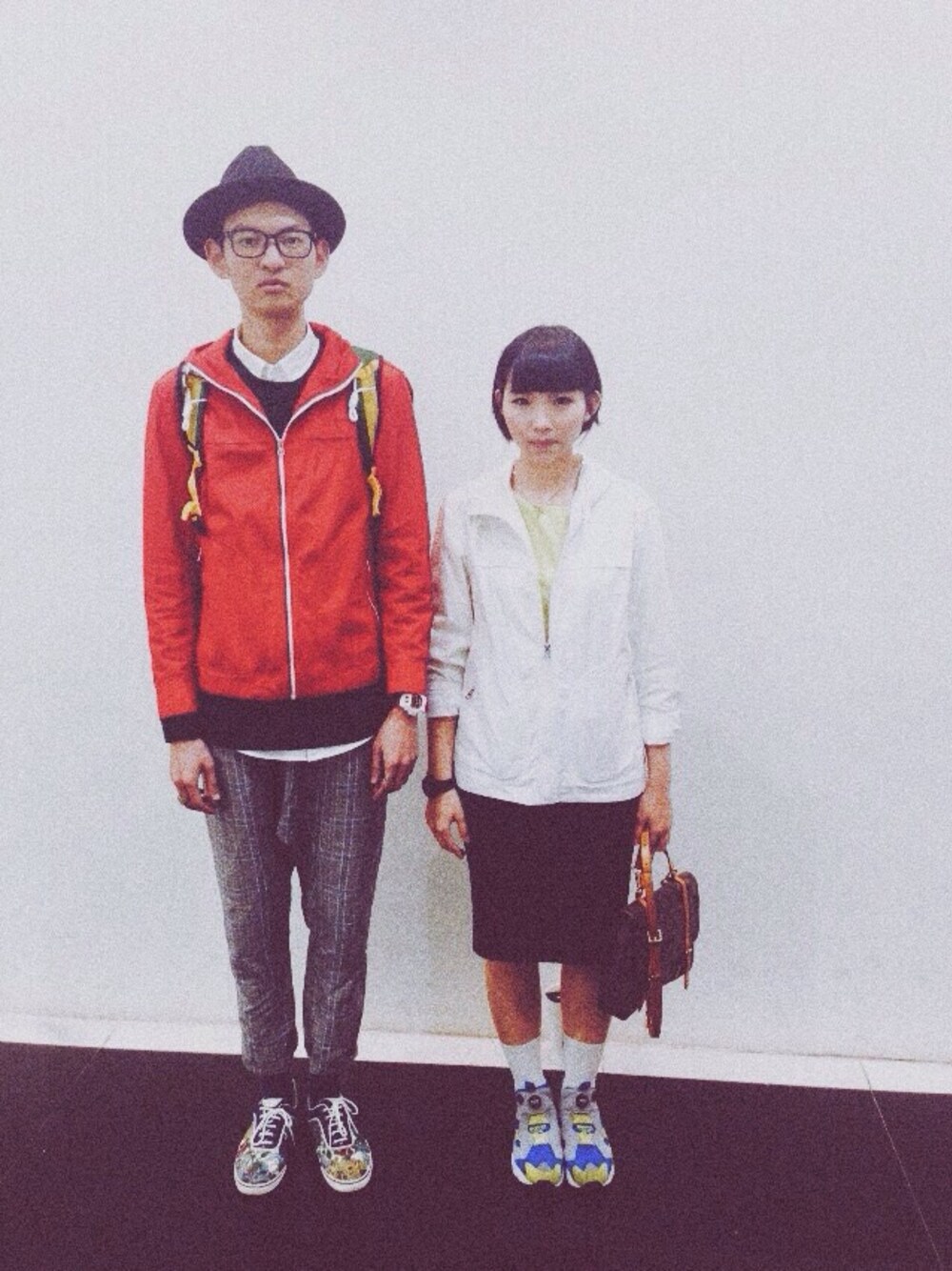 レッド系のライダースジャケット、イエロー系のスニーカー、ブラック系のスカートを着用したレディースの冬コーディネートの1枚目の写真