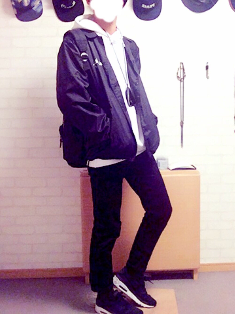 ブラック系のナイロンジャケット、ホワイト系のパーカー、ブラック系のデニムパンツを着用したメンズの冬コーディネートの1枚目の写真