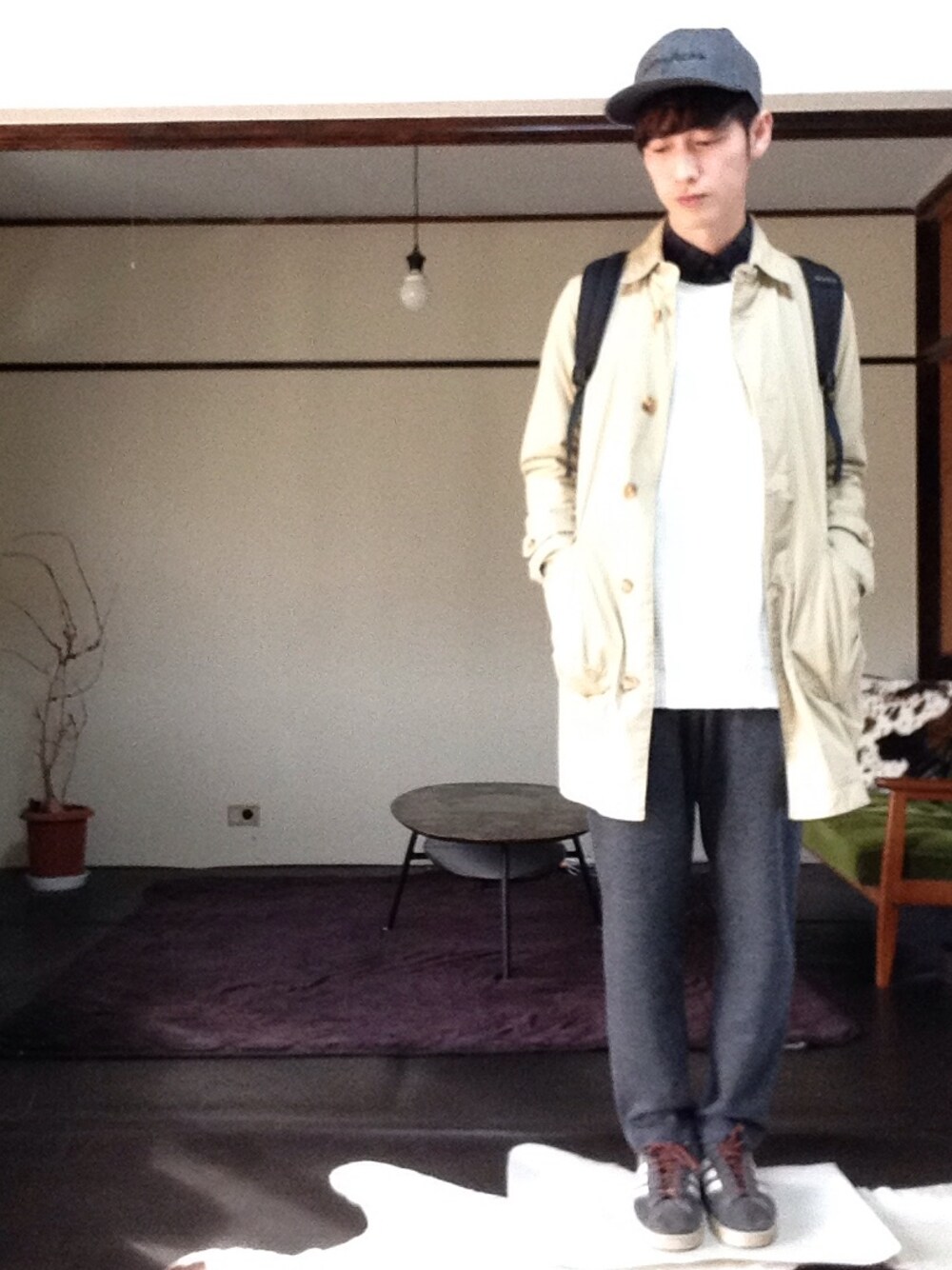 ベージュ系のステンカラーコート、ホワイト系のニット/セーター、グリーン系のシャツ/ブラウスを着用したメンズの秋コーディネートの1枚目の写真