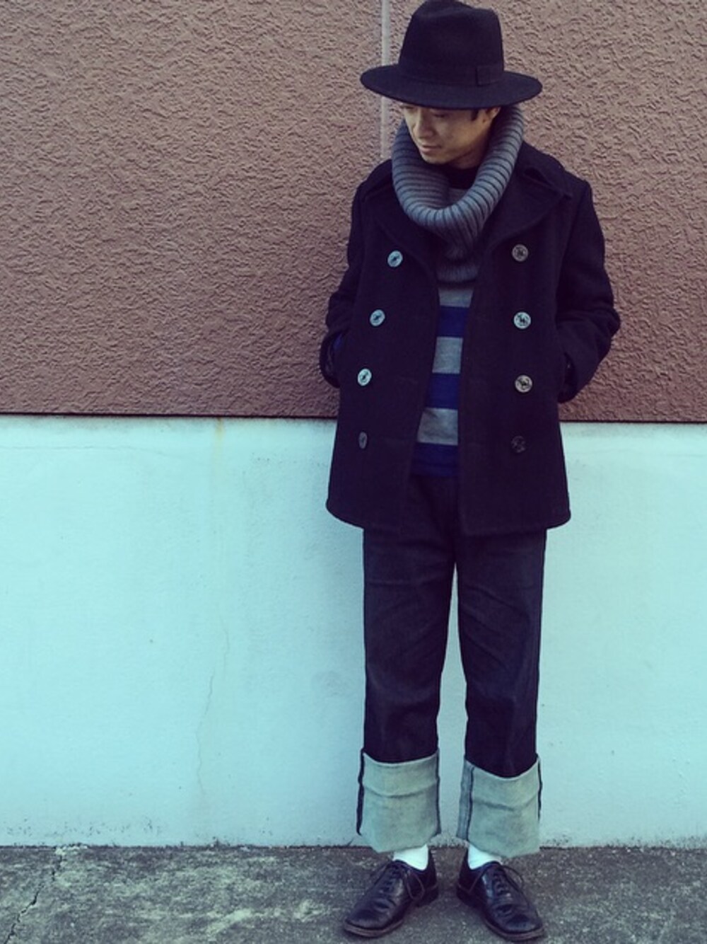 ブラック系のピーコート、ブルー系のニット/セーター、ブルー系のデニムパンツを着用したメンズの冬コーディネートの1枚目の写真
