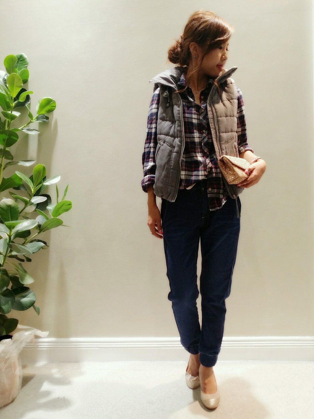 ゴールド系のクラッチバッグ、ブラック系のパンプス、ブルー系のパンツを着用したレディースの秋コーディネートの1枚目の写真