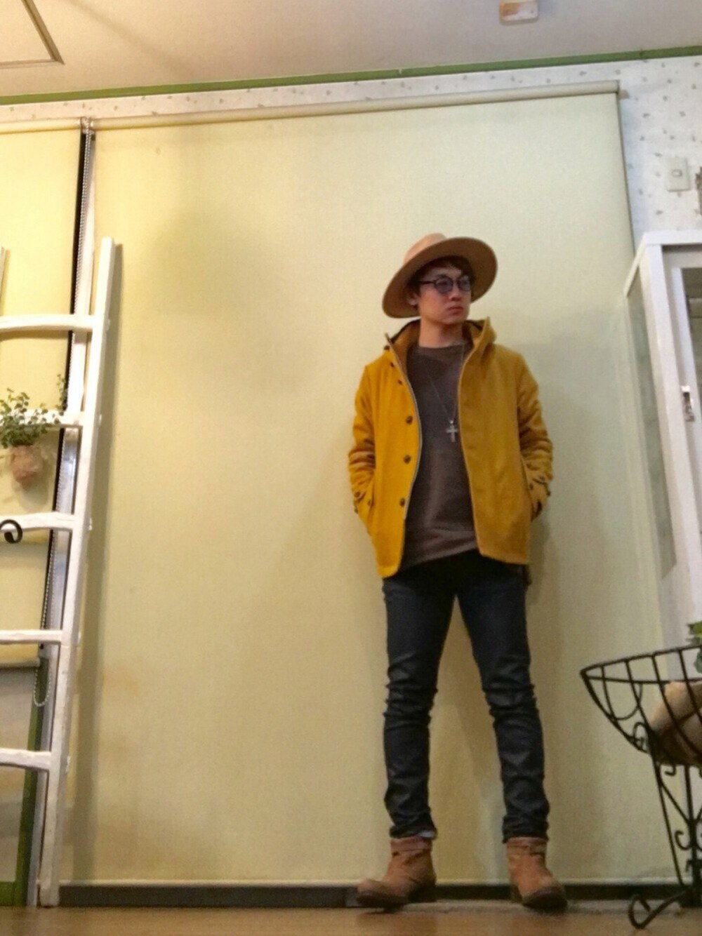 イエロー系のモッズコート、ブラウン系のスウェット、ブルー系のデニムパンツを着用したメンズの冬コーディネートの1枚目の写真