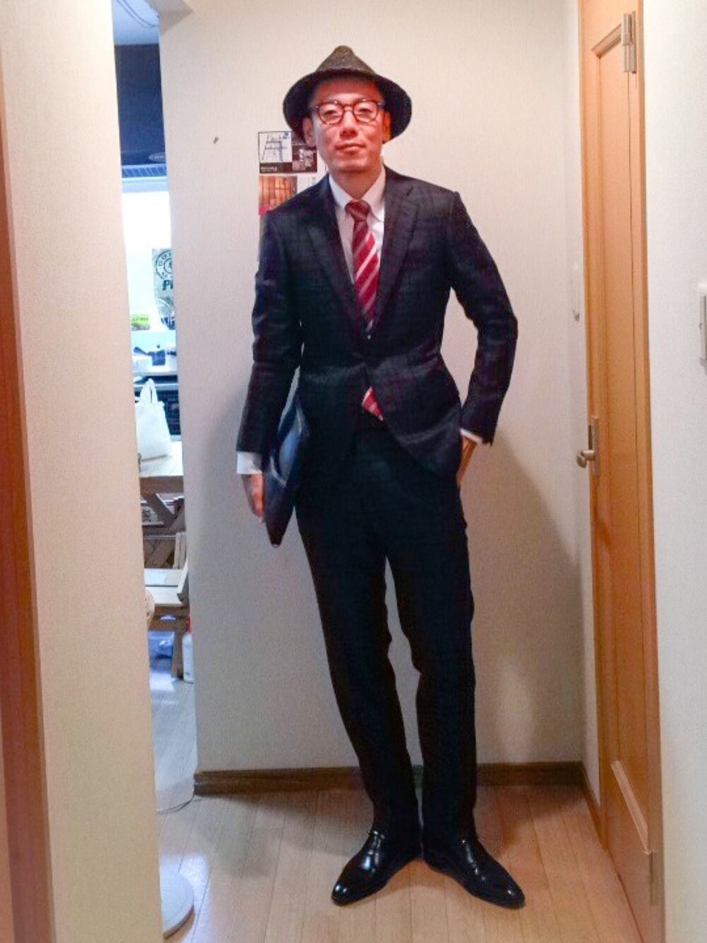 ブラック系のセットアップ、ブラック系のドレスシューズ、ブラック系のクラッチバッグを着用したメンズの秋コーディネートの1枚目の写真