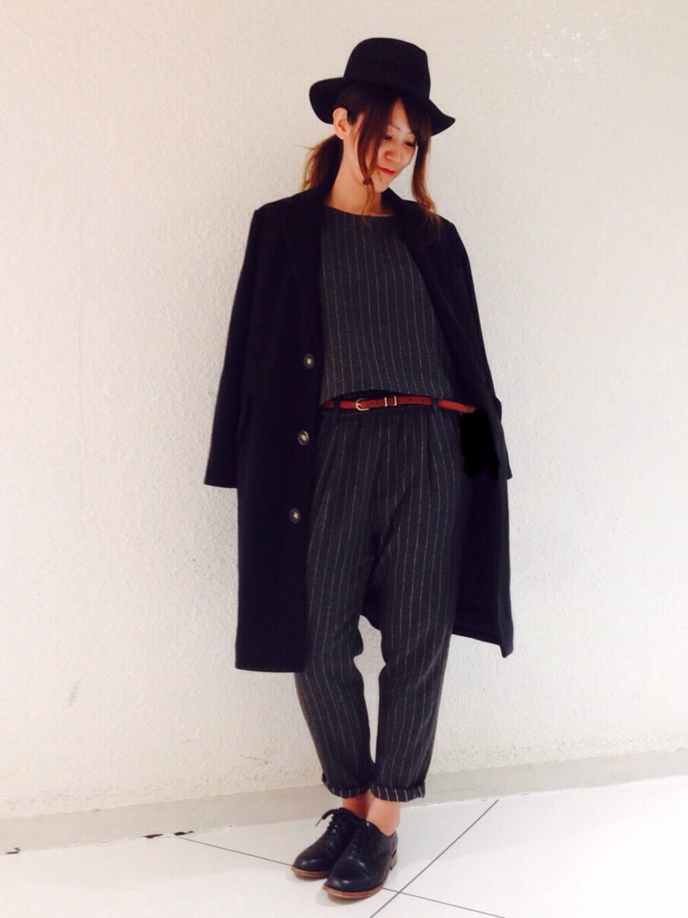 ブラック系のチェスターコート、グレー系のトップス、グレー系のパンツを着用したレディースの冬コーディネートの1枚目の写真