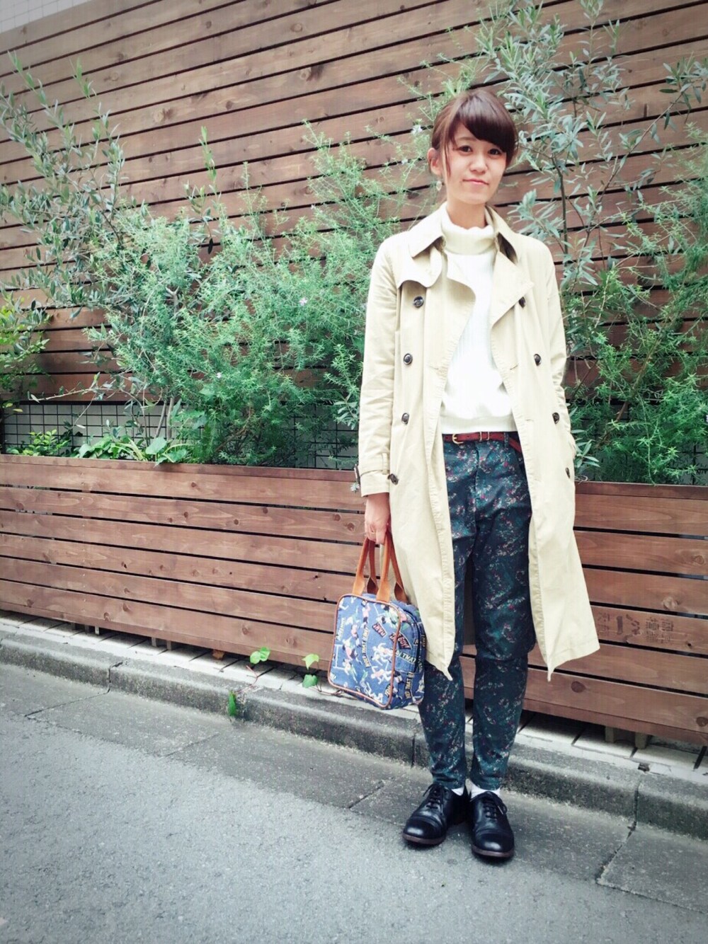 ベージュ系のトレンチコート、グリーン系のパンツ、ブルー系のバッグを着用したレディースの秋コーディネートの1枚目の写真