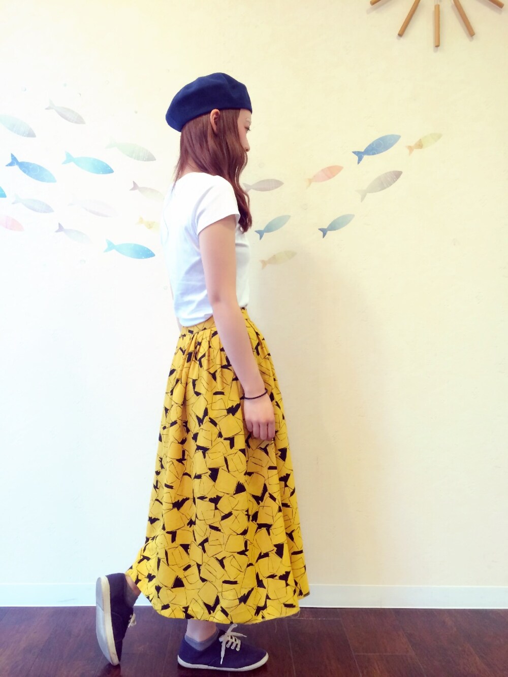 ホワイト系のトップス、イエロー系のスカート、ブルー系のシューズを着用したレディースの夏コーディネートの1枚目の写真