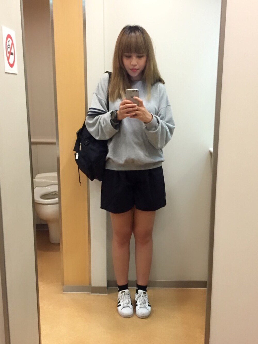 ホワイト系のスニーカー、ブラック系のバッグ、グレー系のトップスを着用したレディースの秋コーディネートの1枚目の写真