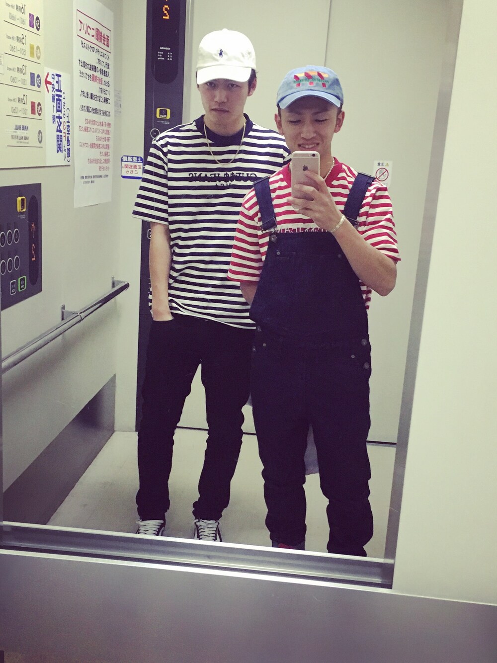 ブルー系のサロペット/オーバーオール、レッド系のTシャツ/カットソー、ブルー系のキャップを着用したメンズの春コーディネートの1枚目の写真