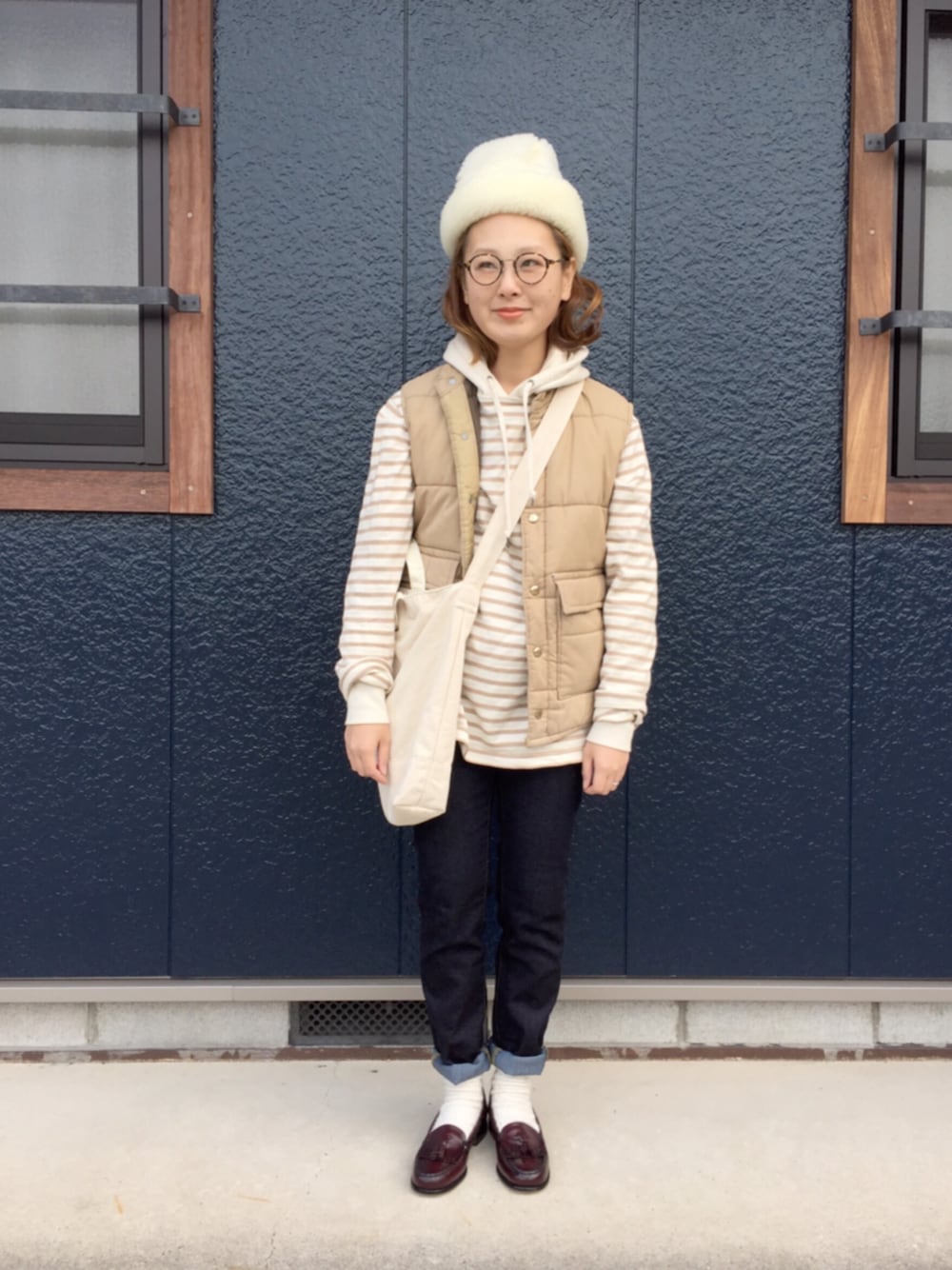 レッド系のモカシン/デッキシューズ、ベージュ系のトートバッグ、ベージュ系のハットを着用したレディースの冬コーディネートの1枚目の写真