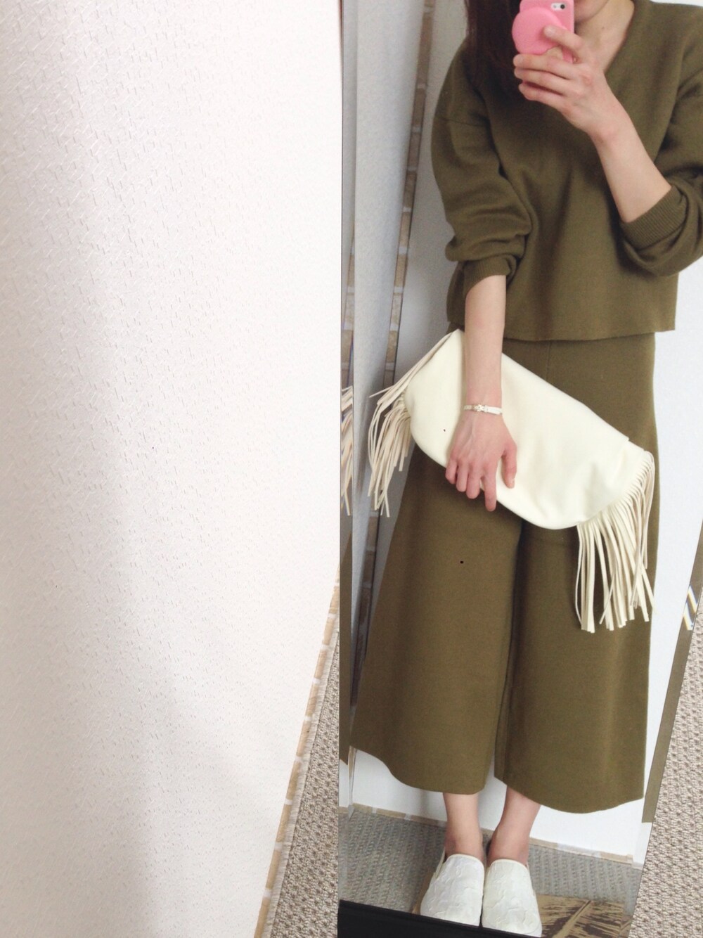 グリーン系のその他パンツ、グリーン系のニット/セーター、ホワイト系のバックパック/リュックを着用したレディースの春コーディネートの1枚目の写真
