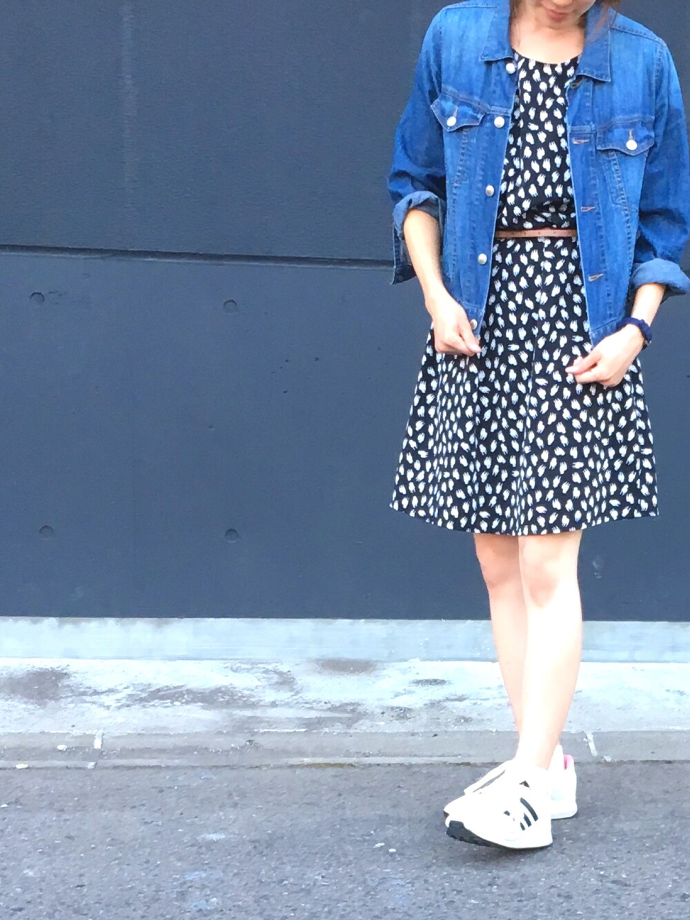 ブルー系のデニムジャケット、ブラック系のワンピース/ドレス、ホワイト系のスニーカーを着用したレディースの秋コーディネートの1枚目の写真