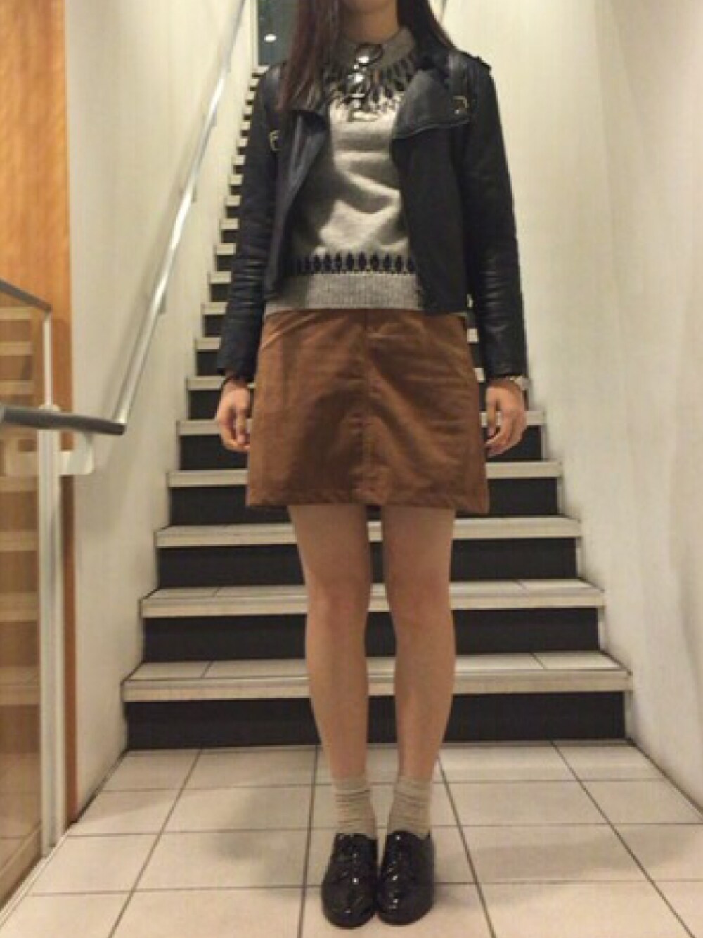 グレー系のニット/セーター、イエロー系のスカート、ブラック系のパンプスを着用したレディースの秋コーディネートの1枚目の写真