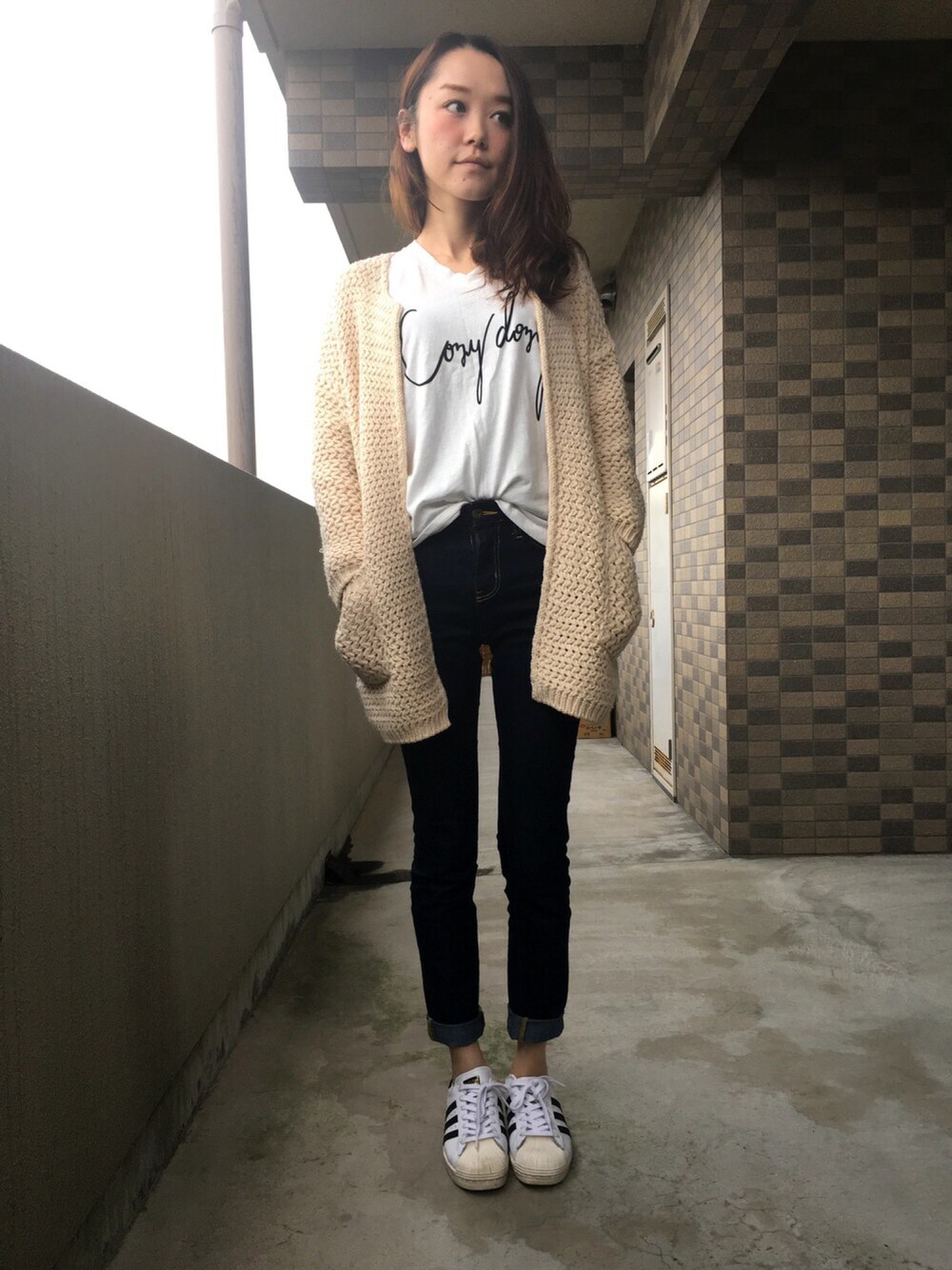 ホワイト系のカーディガン/ボレロ、ホワイト系のTシャツ/カットソー、ブルー系のデニムパンツを着用したレディースの春コーディネートの1枚目の写真