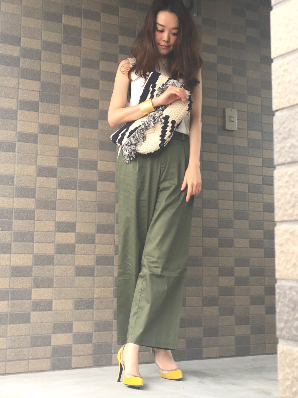 グリーン系のパンツ、ブルー系のクラッチバッグ、イエロー系のパンプスを着用したレディースの夏コーディネートの1枚目の写真