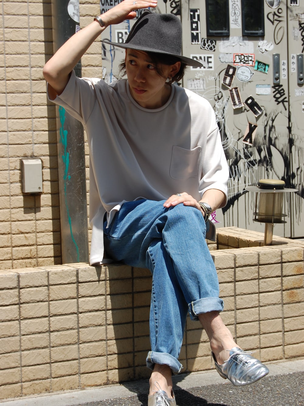 ブルー系のデニムパンツ、ベージュ系のTシャツ/カットソー、グレー系のハットを着用したメンズの春コーディネートの1枚目の写真