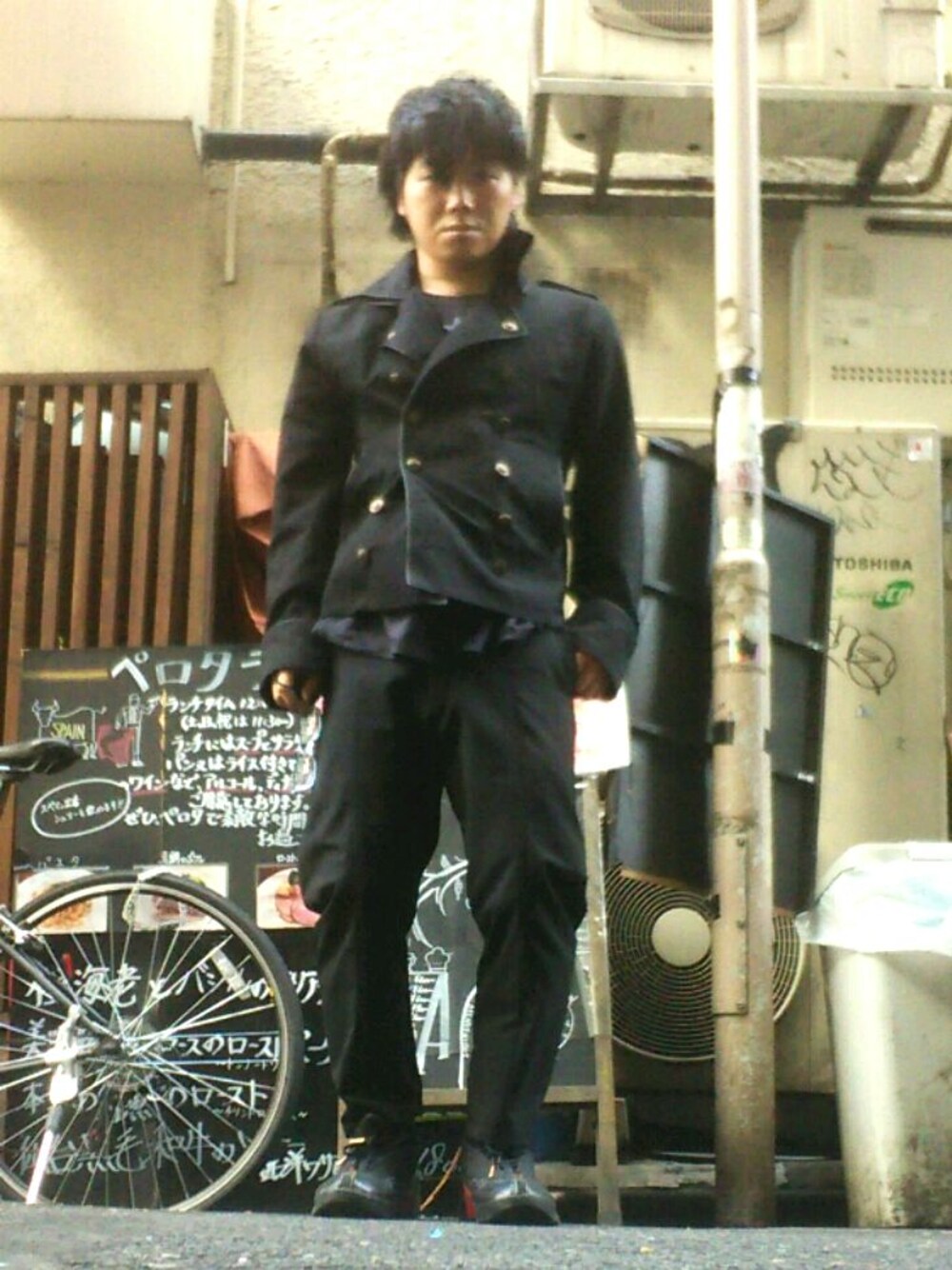 ブラック系のパンツ、ブラック系のピーコート、ブラック系のスニーカーを着用したメンズの春コーディネートの1枚目の写真