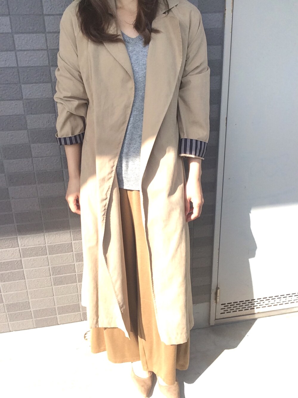 イエロー系のトレンチコート、グレー系のニット/セーター、ブラウン系のその他パンツを着用したレディースの春コーディネートの1枚目の写真