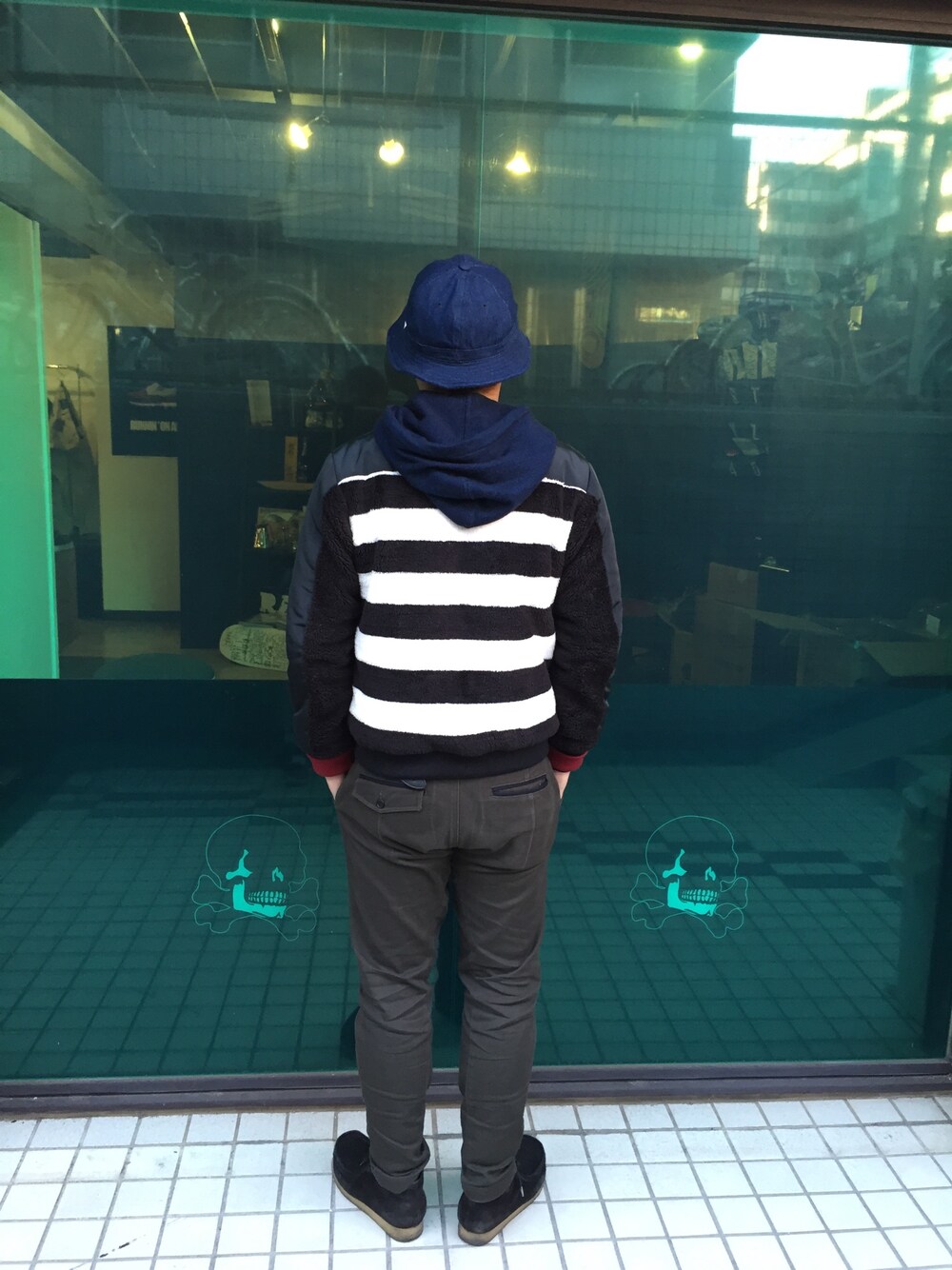 ブラック系のナイロンジャケット、ブルー系のパーカー、グレー系のチノパンツを着用したメンズの冬コーディネートの1枚目の写真