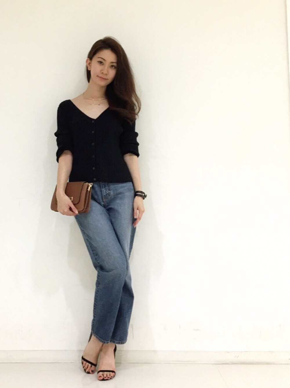 ブラック系のカーディガン/ボレロ、ブルー系のデニムパンツ、ブラウン系のバッグを着用したレディースの秋コーディネートの1枚目の写真