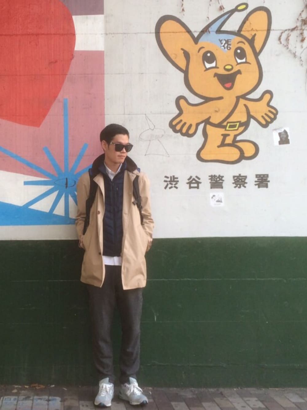 ベージュ系のステンカラーコート、ベージュ系のステンカラーコート、ブルー系のダウンベストを着用したメンズの冬コーディネートの1枚目の写真