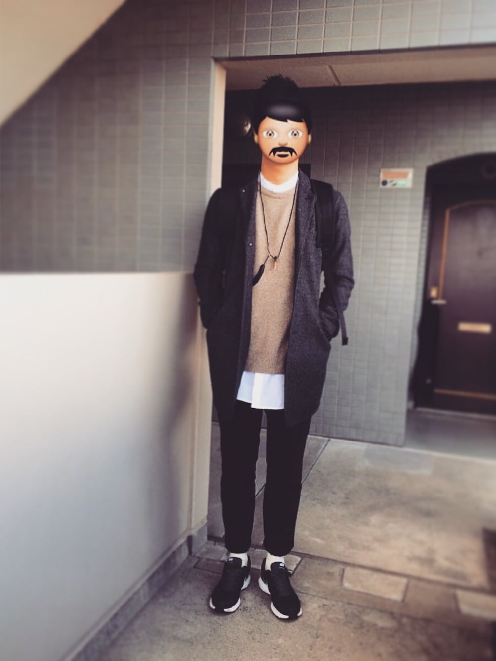 グレー系のチェスターコート、ベージュ系のニット/セーター、ホワイト系のシャツ/ブラウスを着用したメンズの冬コーディネートの1枚目の写真