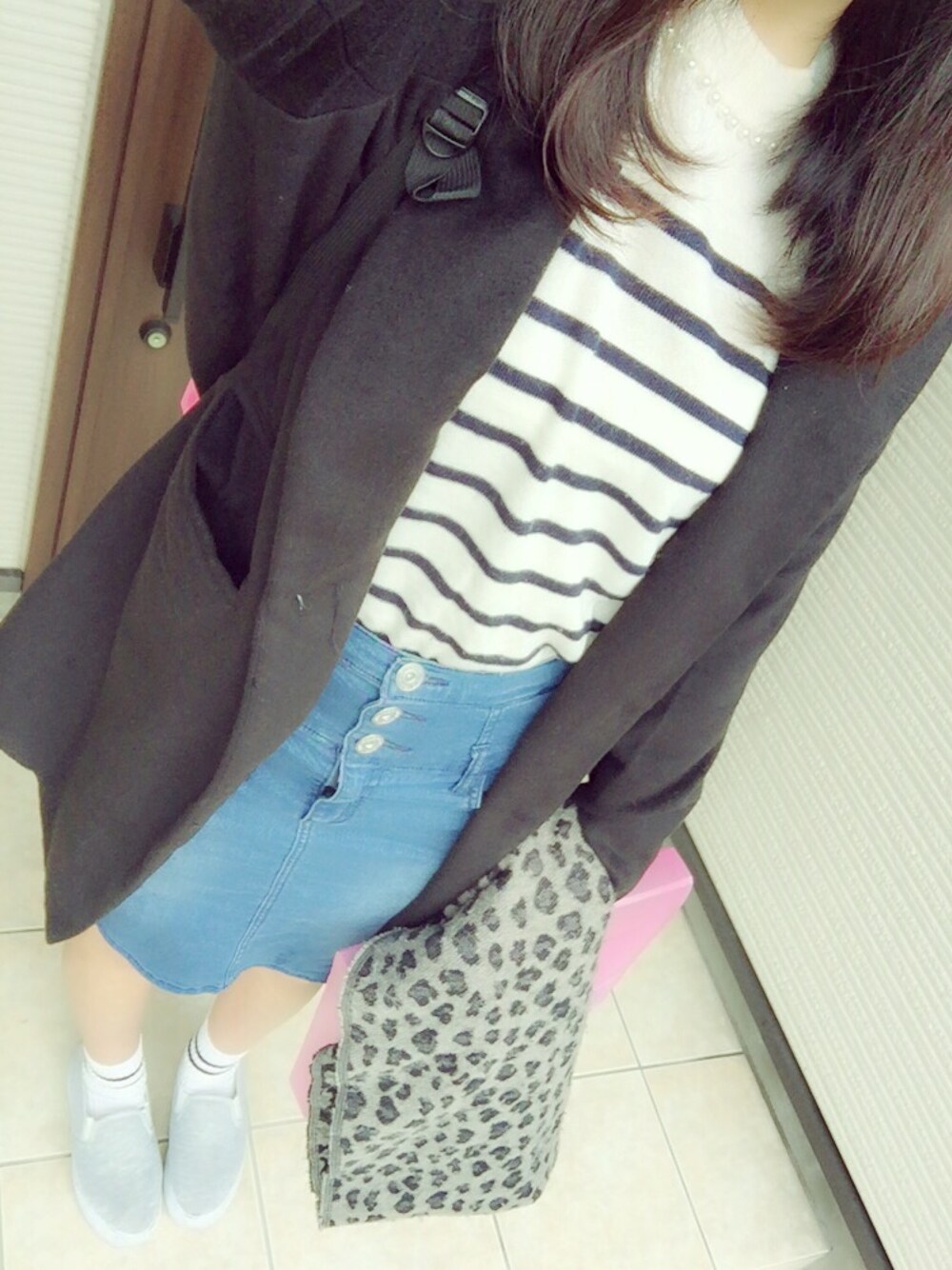 ホワイト系のニット/セーター、ブルー系のデニムスカート、ブラック系のチェスターコートを着用したレディースの秋コーディネートの1枚目の写真