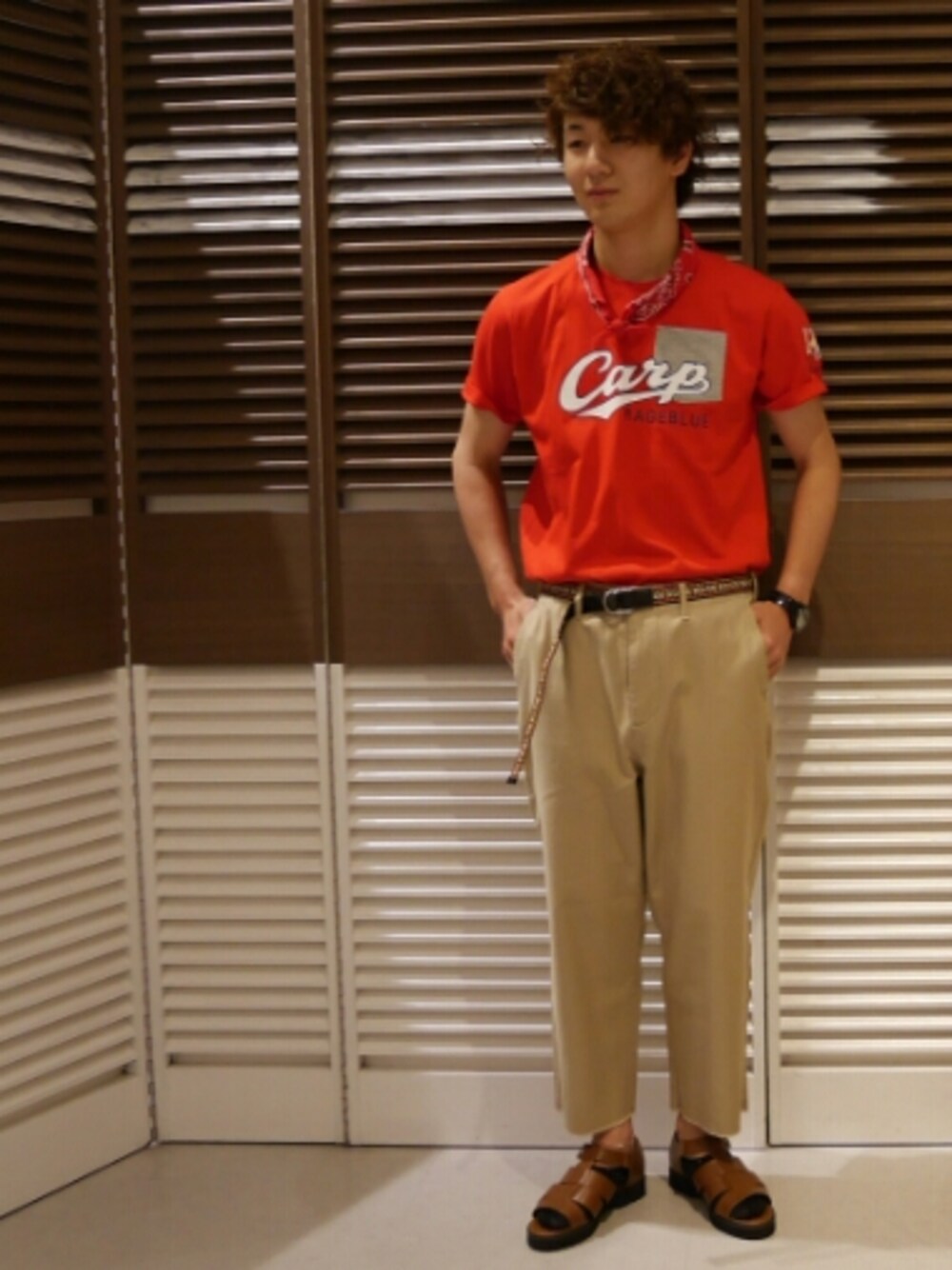 ブラウン系のサンダル、レッド系のTシャツ/カットソー、ベージュ系のパンツを着用したメンズの夏コーディネートの1枚目の写真