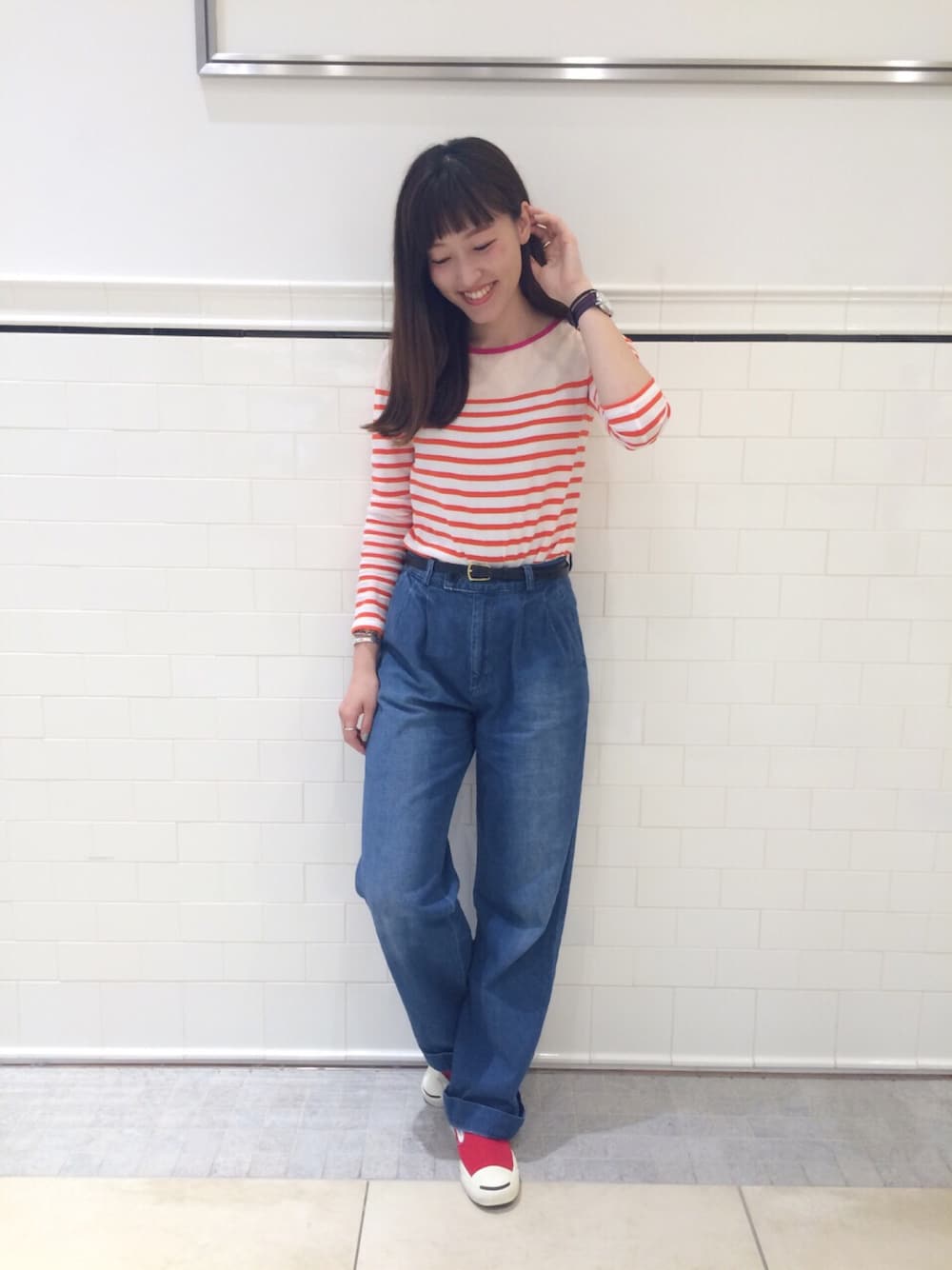 オレンジ系のTシャツ/カットソー、レッド系のスニーカー、ブルー系のデニムパンツを着用したレディースの春コーディネートの1枚目の写真