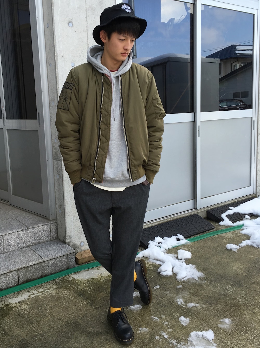 ブラック系のブーツ、グレー系のスラックス、グレー系のパーカーを着用したメンズの冬コーディネートの1枚目の写真