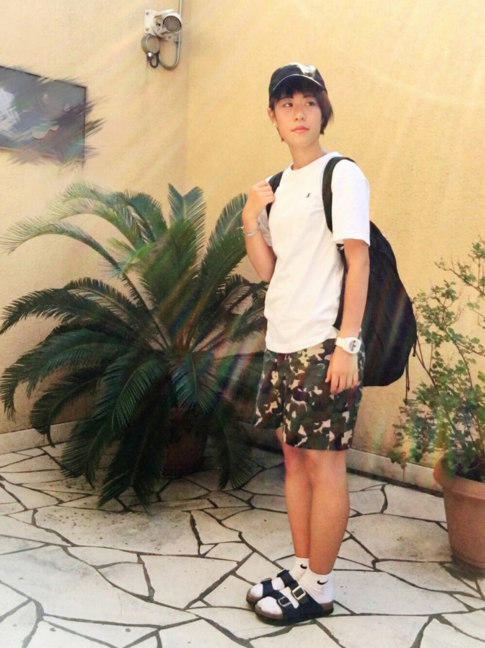 ホワイト系のTシャツ/カットソー、ブラック系のバックパック/リュック、グリーン系のスカートを着用したレディースの夏コーディネートの1枚目の写真