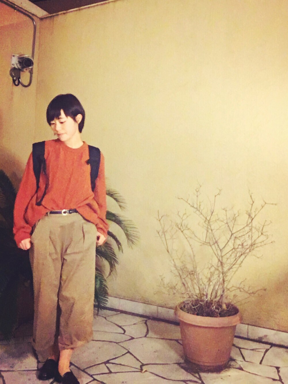 オレンジ系のニット/セーター、ベージュ系のその他パンツ、ブラック系のバックパック/リュックを着用したレディースの冬コーディネートの1枚目の写真