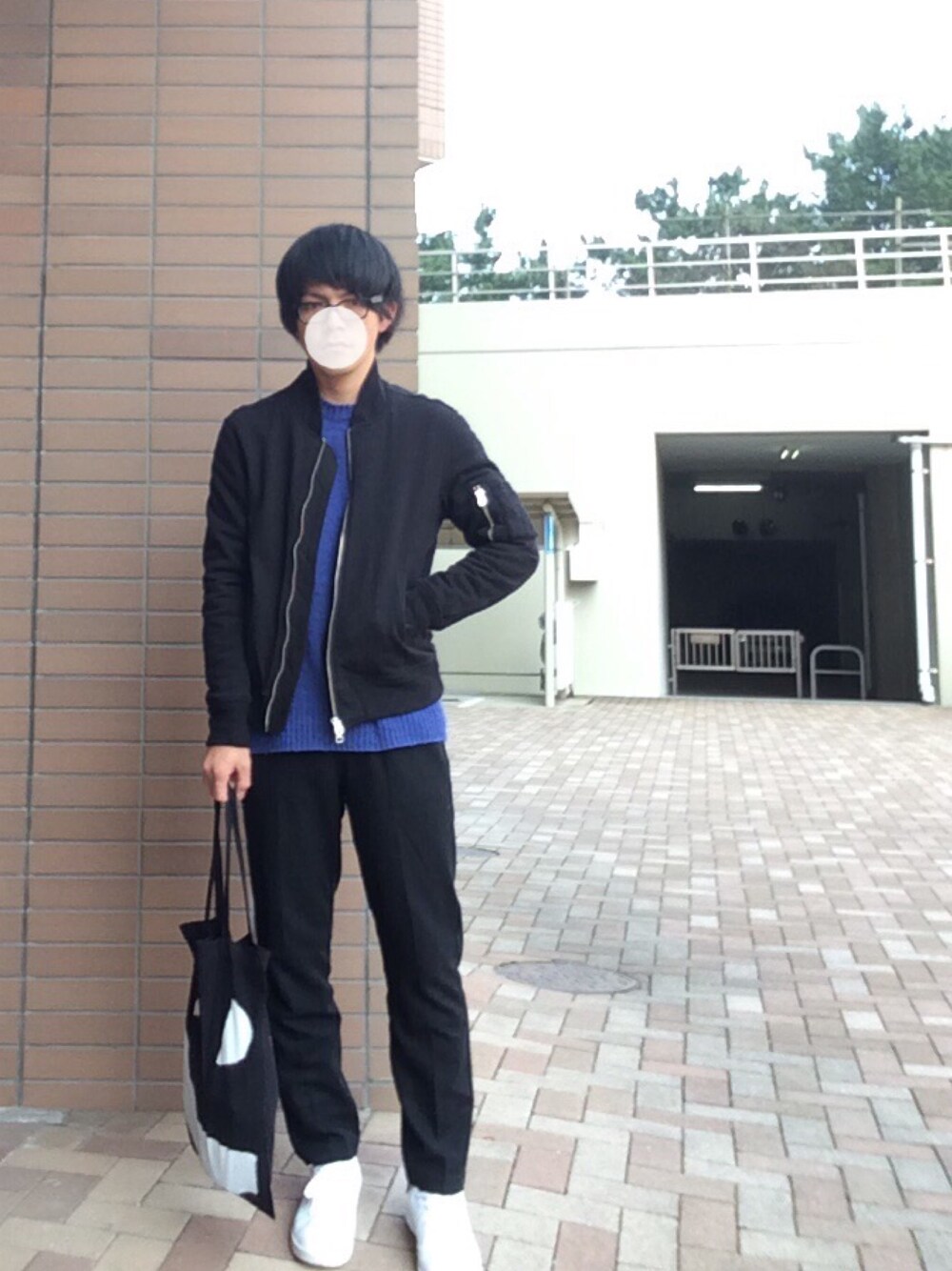 ブルー系のニット/セーター、ブラック系のナイロンジャケット、ブラック系のスラックスを着用したメンズの冬コーディネートの1枚目の写真