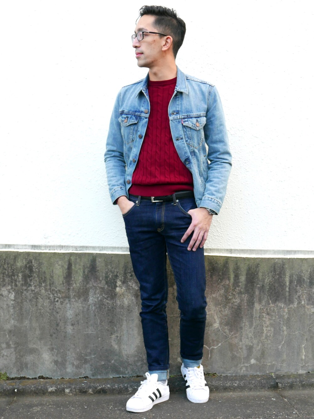 ブルー系のデニムパンツ、ホワイト系のスニーカー、レッド系のニット/セーターを着用したメンズの秋コーディネートの1枚目の写真