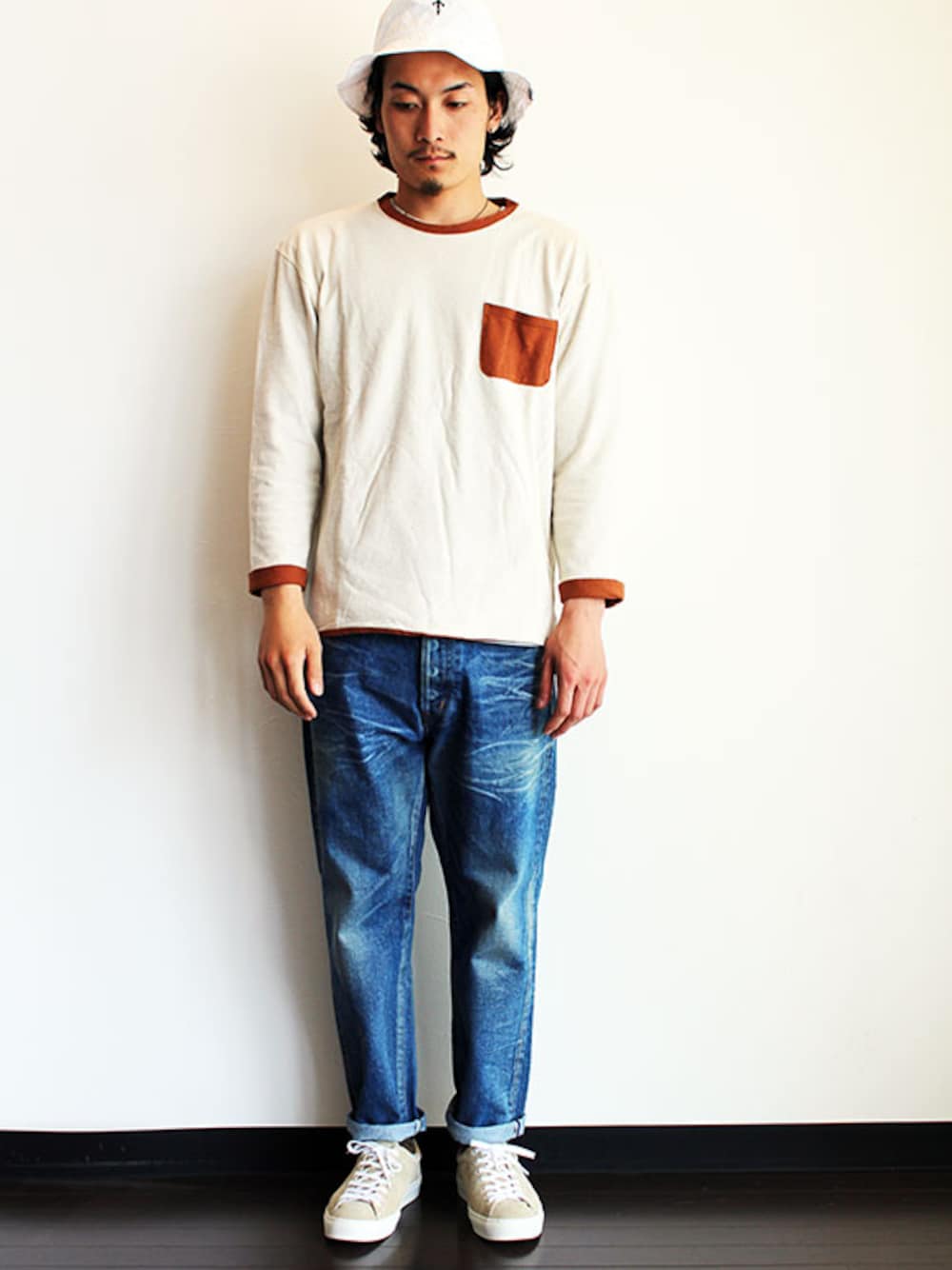 ベージュ系のTシャツ/カットソー、ブルー系のデニムパンツ、ベージュ系のスニーカーを着用したメンズの春コーディネートの1枚目の写真