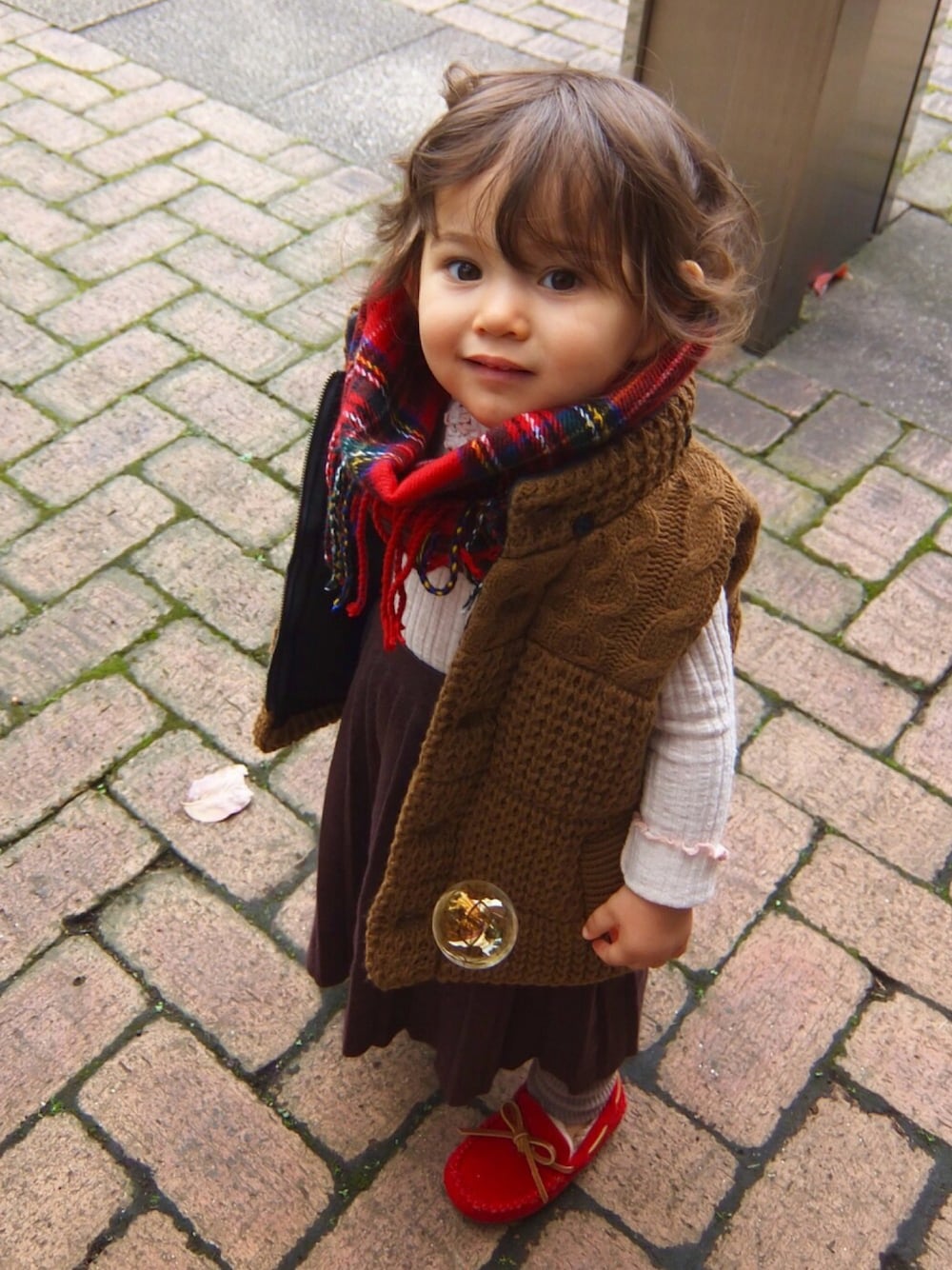 レッド系のモカシン/デッキシューズ、ベージュ系のTシャツ/カットソー、その他のダウンベストを着用したキッズの秋コーディネートの1枚目の写真