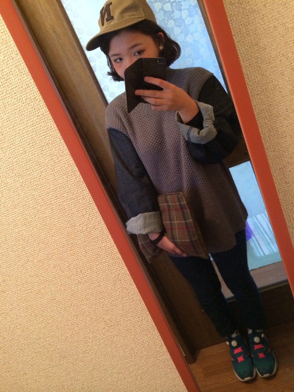 グレー系のニット/セーター、ブラウン系のクラッチバッグ、グリーン系のスニーカーを着用したレディースの秋コーディネートの1枚目の写真